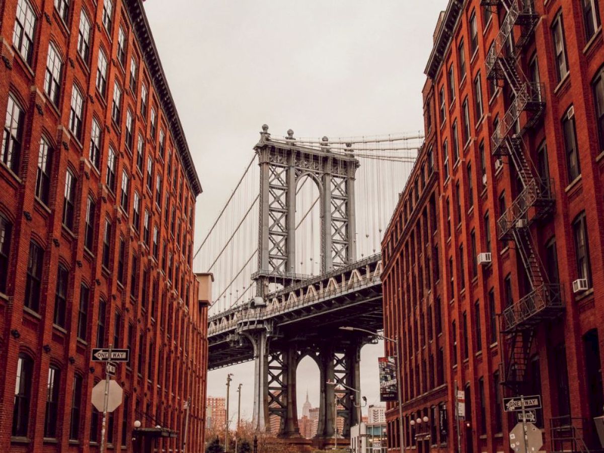 An iconic bridge spans between two rows of red brick buildings, with a clear view through the street. This scene captures urban architecture beautifully.